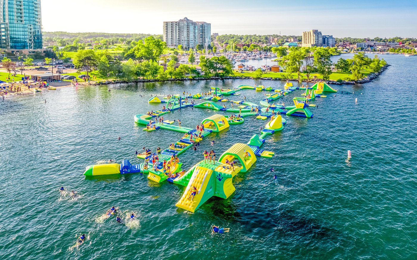 Floating water park in Barrie, Ontario with people enjoying inflatable slides and obstacles. Takeoff-Moving Toronto