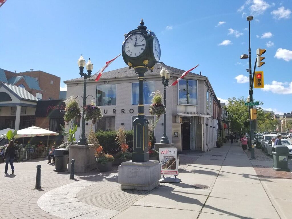 Downtown Oakville street with clock tower, shops, and Canadian flags. Takeoff-Moving Toronto